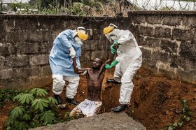 Hír kategória, első hely: egy végső stádiumos ebolás beteget emelnek ki az őrök a gödörből, aki hallucinálni kezdett, és szökni próbált a karanténból. A férfi nem sokkal a kép készítése után belehalt betegségébe. (Fotó: Pete Muller / World Press Photo)
