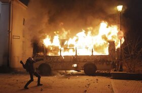 A protester  throws  a stone towards a burning police bus in front of him, during clashes with police,  in central Kiev, Ukraine, Sunday, Jan. 19, 2014. Hundreds of protesters on Sunday clashed with riot police in the center of the Ukrainian capital, afte