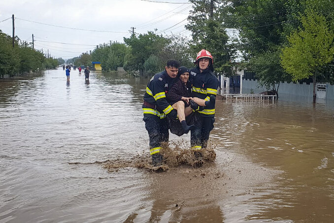 A tűzoltók egy idős nőt menekítenek az áradással sújtott romániai Pechea településen (Fotó: Beta/AP/ISU Galati)