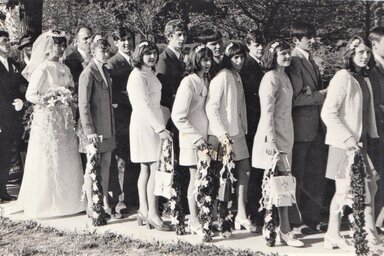 Szilágyi lakodalmas menet a templomkert előtt 1972-ben. A nyoszolyúlányok bukszussal és krepp papírvirágokkal díszített fokost, a vőfények pedig csutorát visznek (Dampfinger Irén gyűjteményé