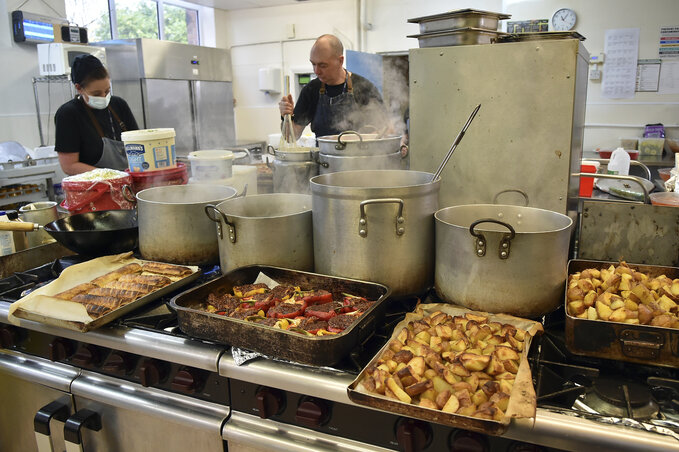 Catering manager Matthew Wright, center, prepares meals at Hillstone Primary School, in Birmingham, England, Wednesday, Nov. 30, 2022. For some children in low-income areas in England, a sch