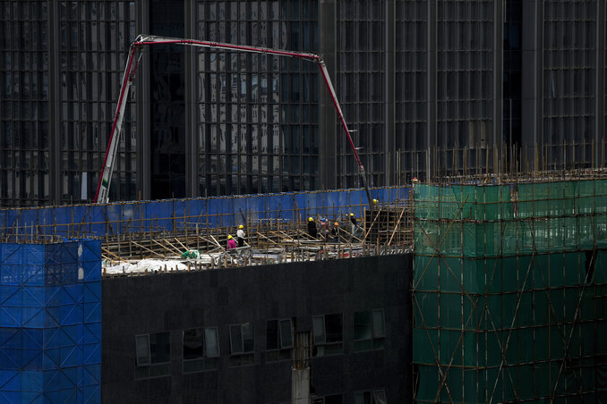 Workers use a machine to pour cement on a reconstruction office building in Beijing on Aug. 6, 2023. China’s government skipped giving an update on a politically sensitive spike in unemploym